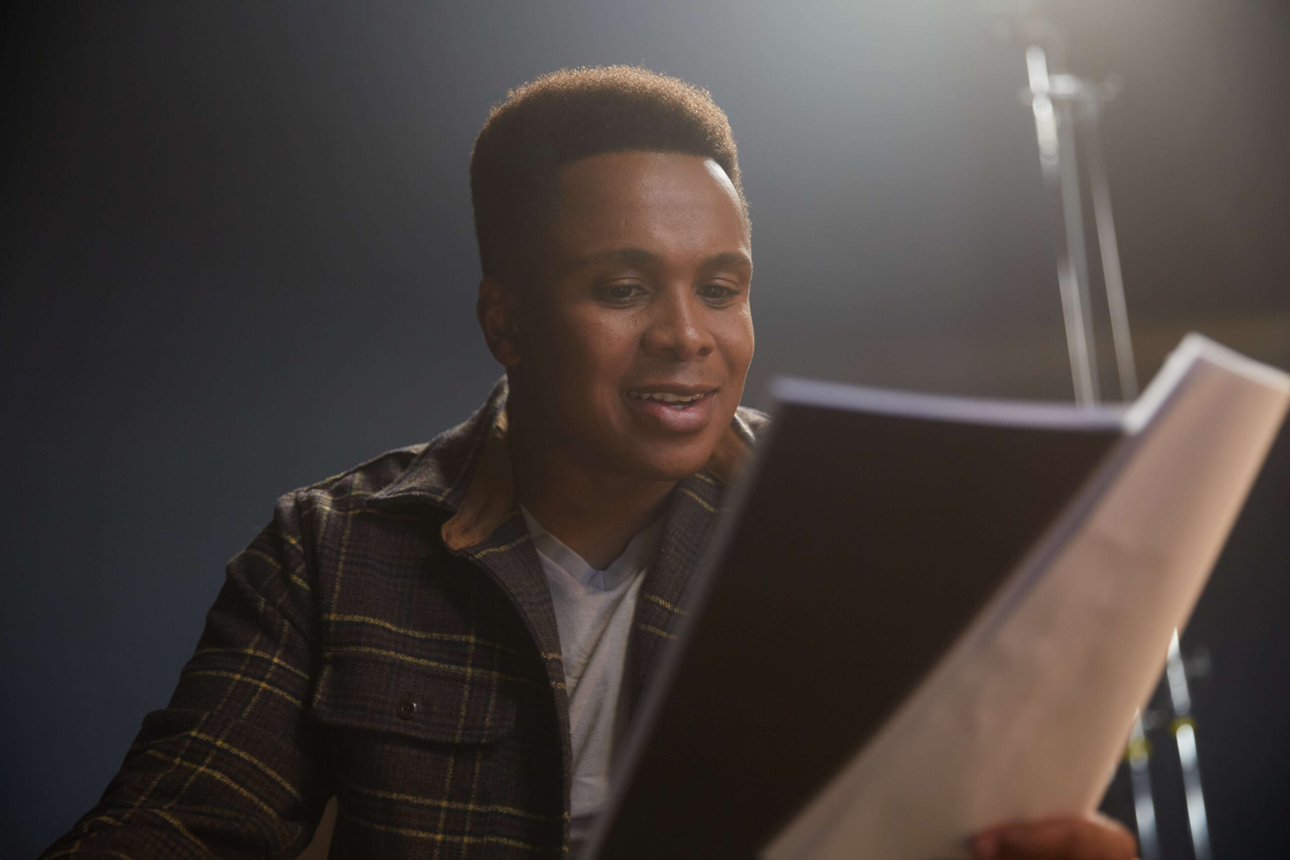 An actor smiling down at a script
