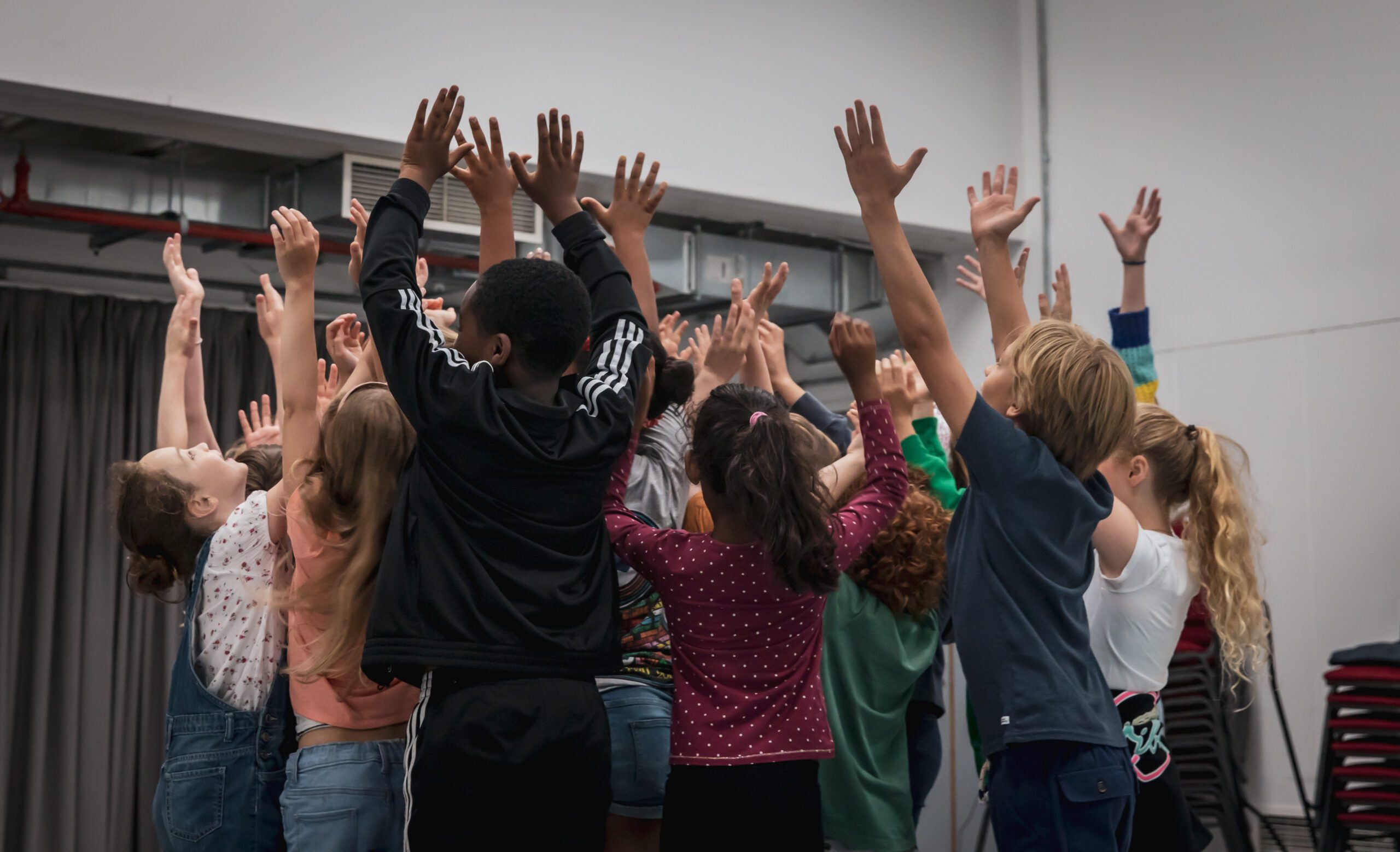 A group of young performers with their arms in the air